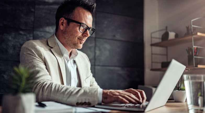 A person in a suit typing on a computer